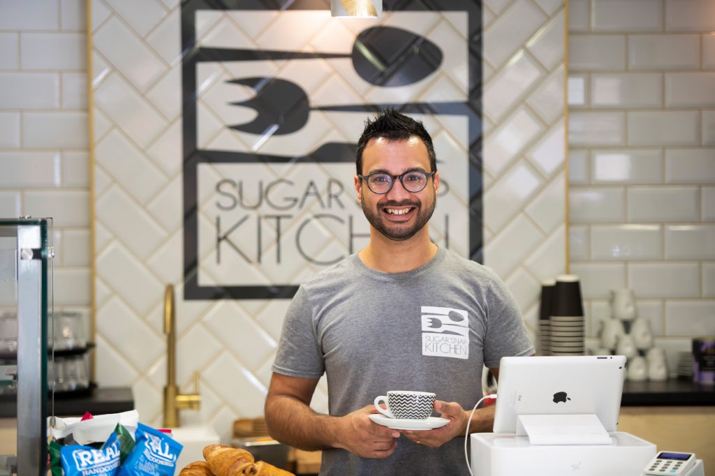 A Sugar Snap Kitchen team member holding a coffee at the café counter